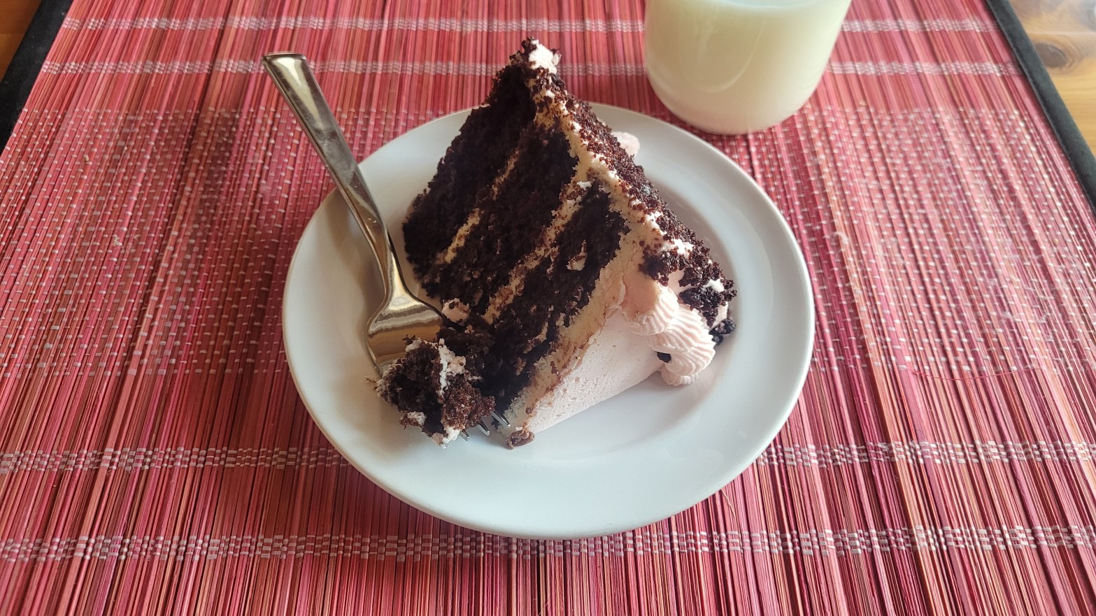 A generous slice of chocolate cake with strawberry icing.